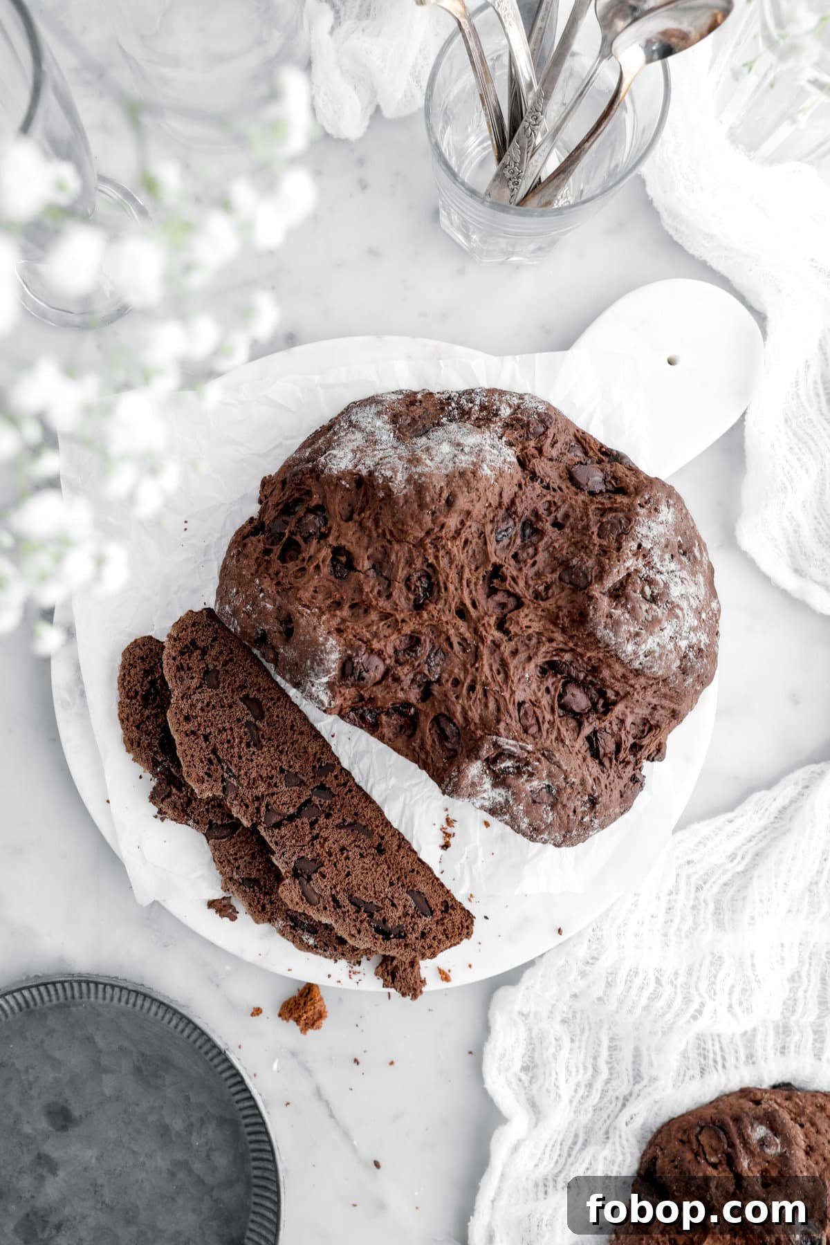 Double Chocolate Irish Stout Soda Bread Recipe for Rich Treat 3 overhead image of chocolate soda bread with two slices laying in front on parchment lined marble tray.