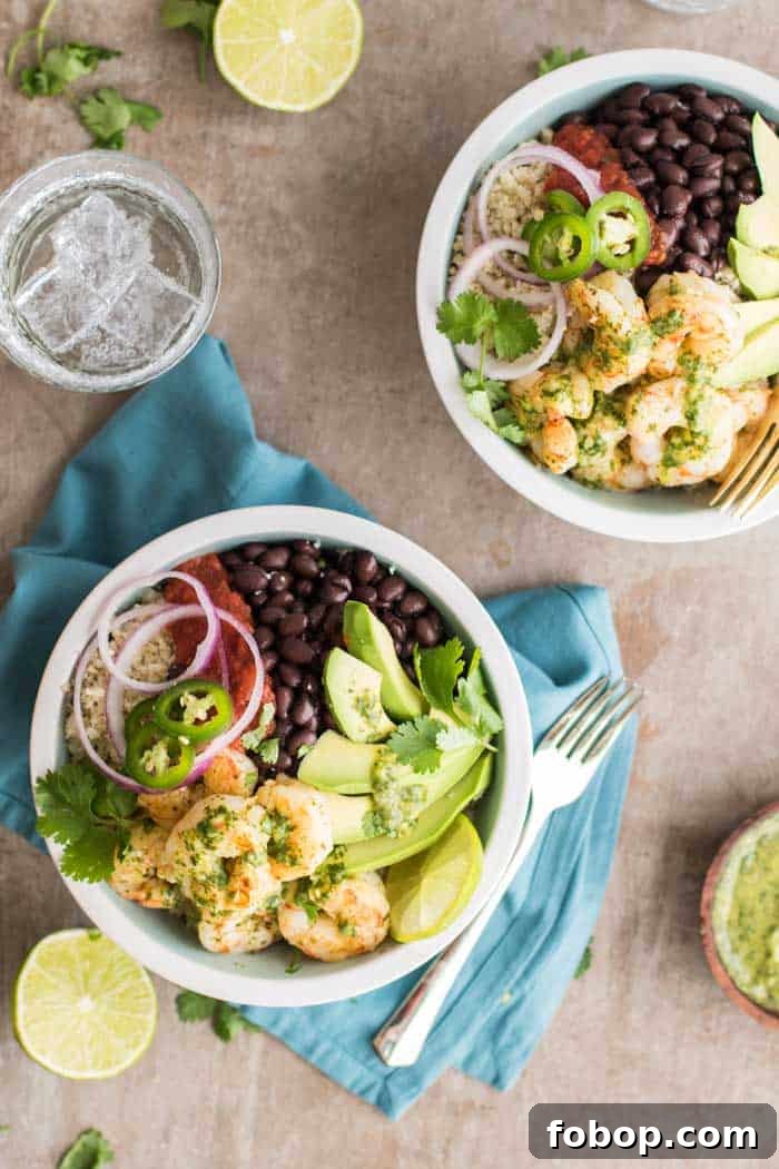 Two bowls filled with cauliflower rice, shrimp, black beans and avocado.
