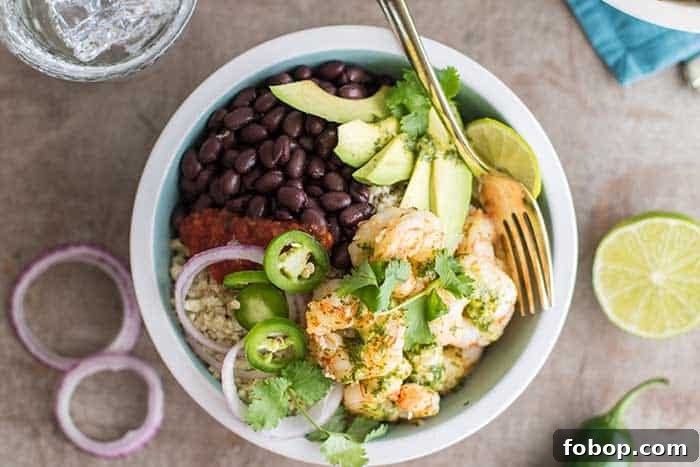 A top view of shrimp burrito bowls loaded with cauliflower rice, black beans, avocado, salsa and onions.