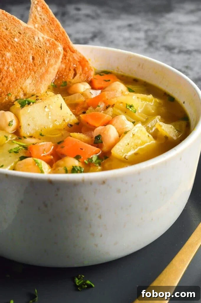 Comforting Vegan Potato and Chickpea Stew Recipe 6 Close up of a bowl of stew with visible chunks of potatoes, carrots and chickpeas
