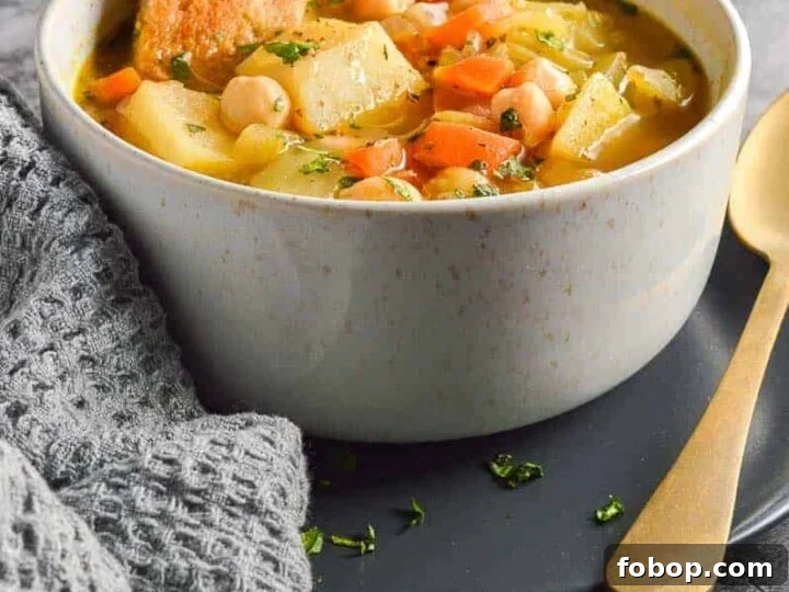A beige bowl with chunks of potato and carrots in broth and two pieces of toast