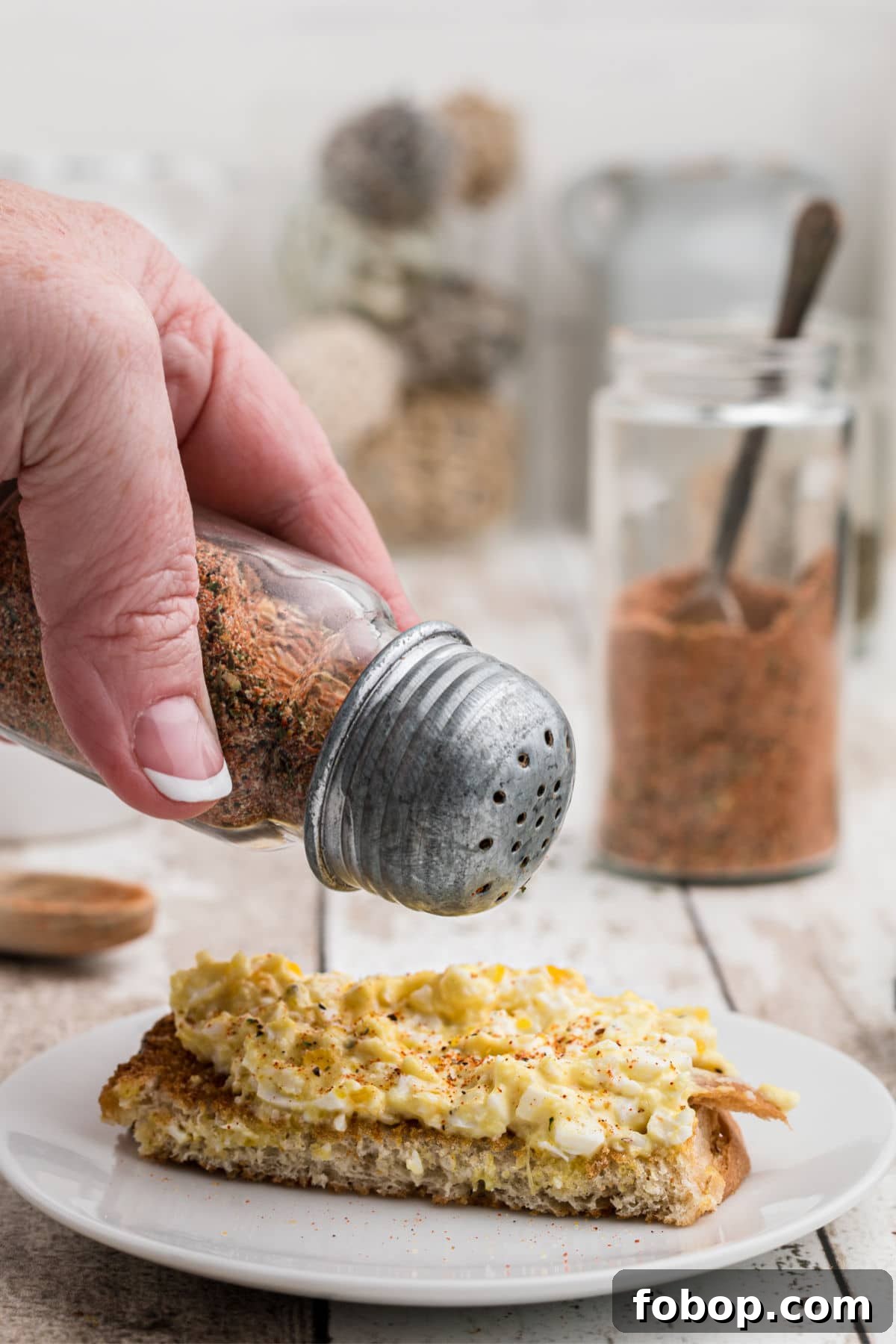 Authentic Homemade Creole Seasoning Recipe for Bold Flavor 5 using a salt shake to season some eggs on toast