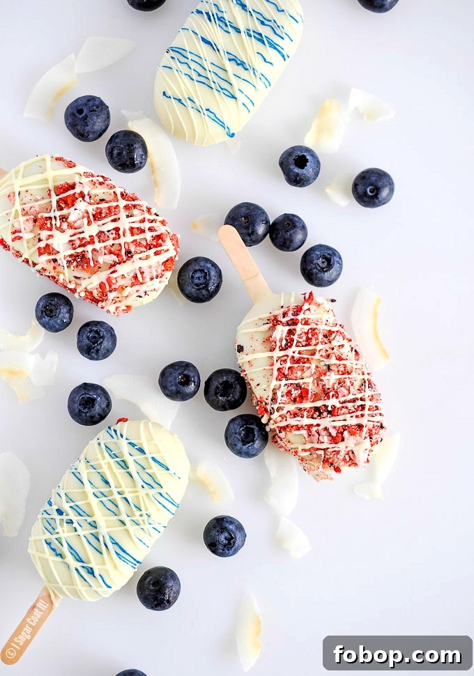 Blueberry Coconut Popsicles are a delightful blend of berries, coconut yogurt and milk dipped in decadent white chocolate and toasted coconut and freeze-dried berries.