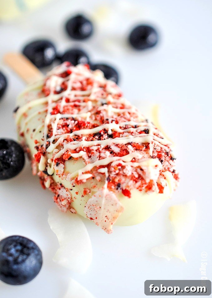 Blueberry Coconut Popsicles are a delightful blend of berries, coconut yogurt and milk dipped in decadent white chocolate and toasted coconut and freeze-dried berries.