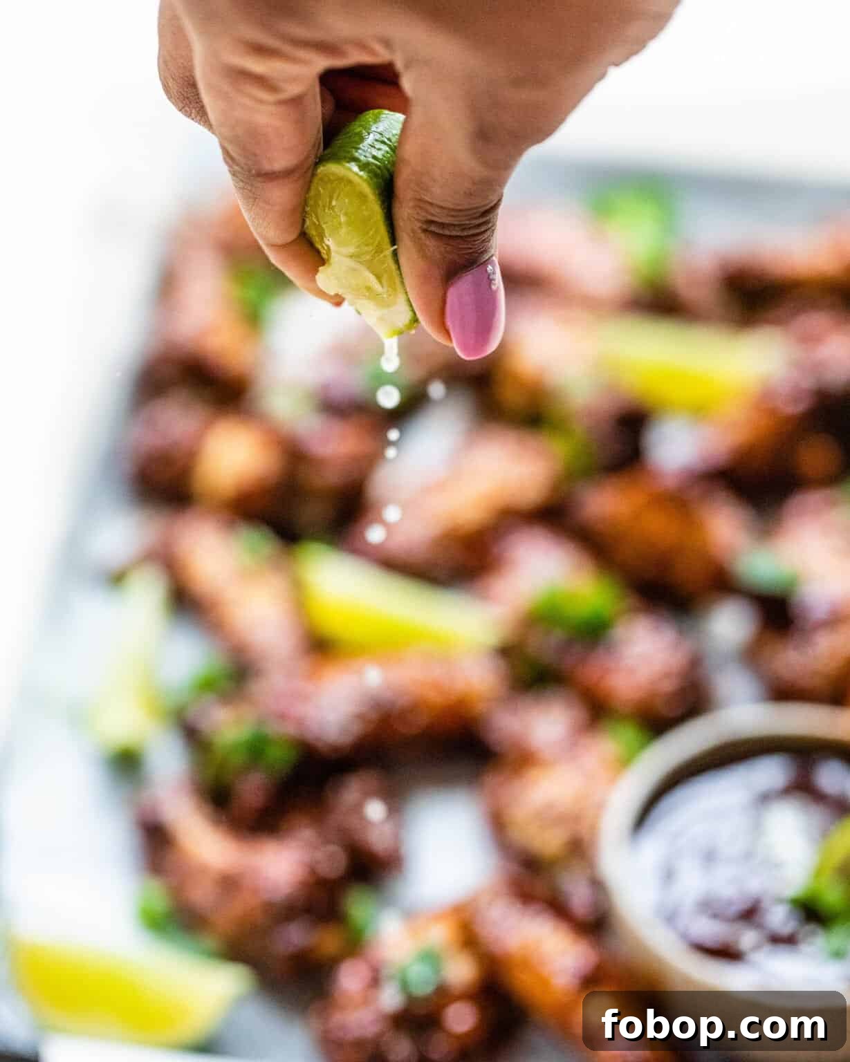 Crispy Cajun BBQ Oven Wings: Super Crunchy Baked Recipe 6 a hand squeezing a lime on top of the cajun bbq wings