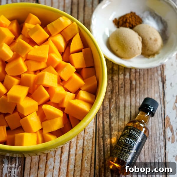 Bourbon-Cinnamon Roasted Butternut Squash Recipe 6 A bowl of peeled and chopped butternut squash sits next to a small bottle of bourbon and a bowl of spices.