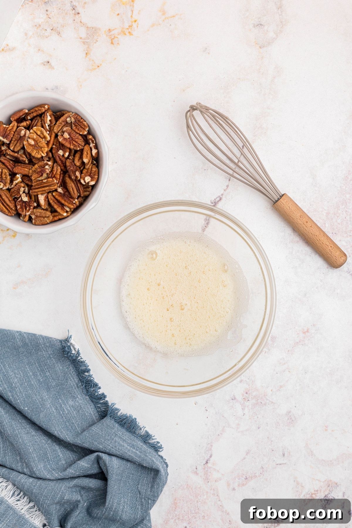 Egg white whisked with water in a clear glass bowl. 