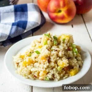 Quinoa, Rice and Peach Salad on a small white plate with fresh peaches in the background.