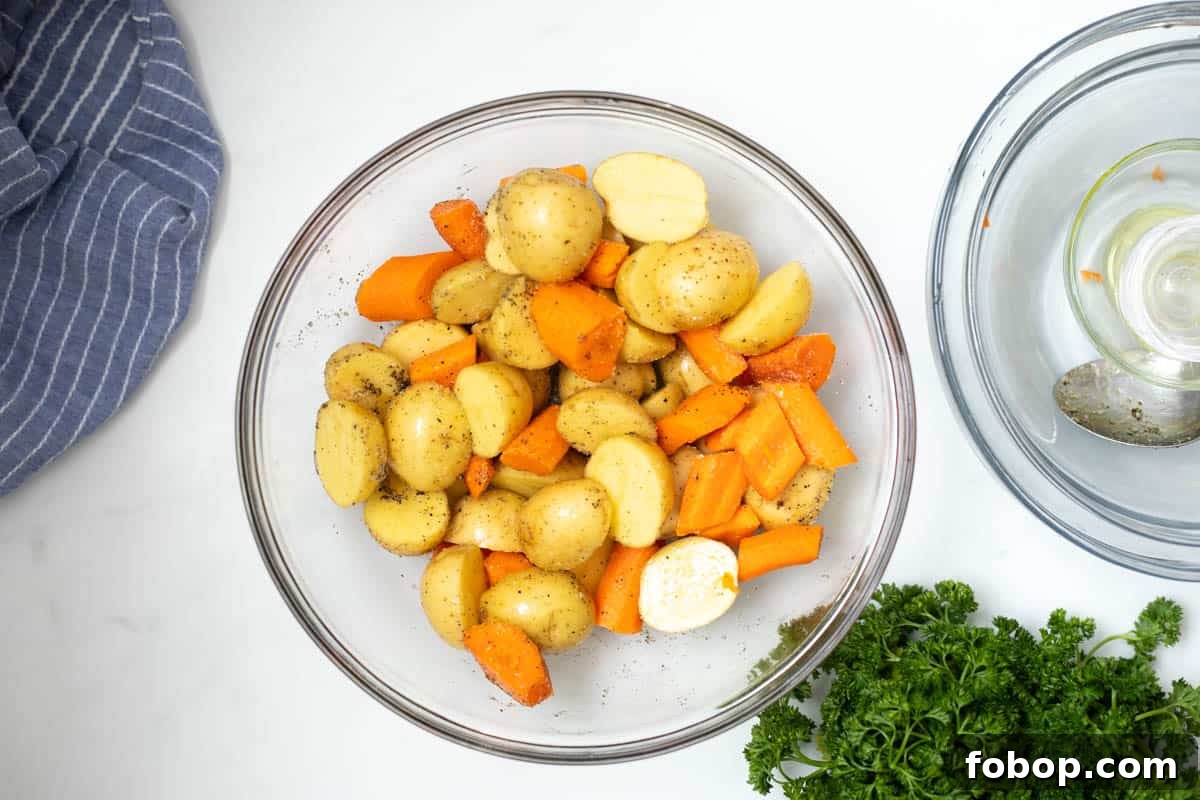 Roasted Carrots and Potatoes Mixing bowl with halved potatoes and carrots tossed with oil and salt and pepper.