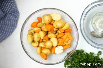 Crispy Roasted Carrots and Potatoes with Garlic and Herbs 3 Mixing bowl with halved potatoes and carrots tossed with oil and salt and pepper.