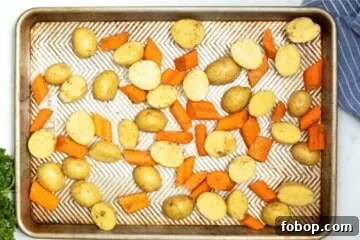 Crispy Roasted Carrots and Potatoes with Garlic and Herbs 4 Seasoned potatoes and carrots spread out on sheet pan.