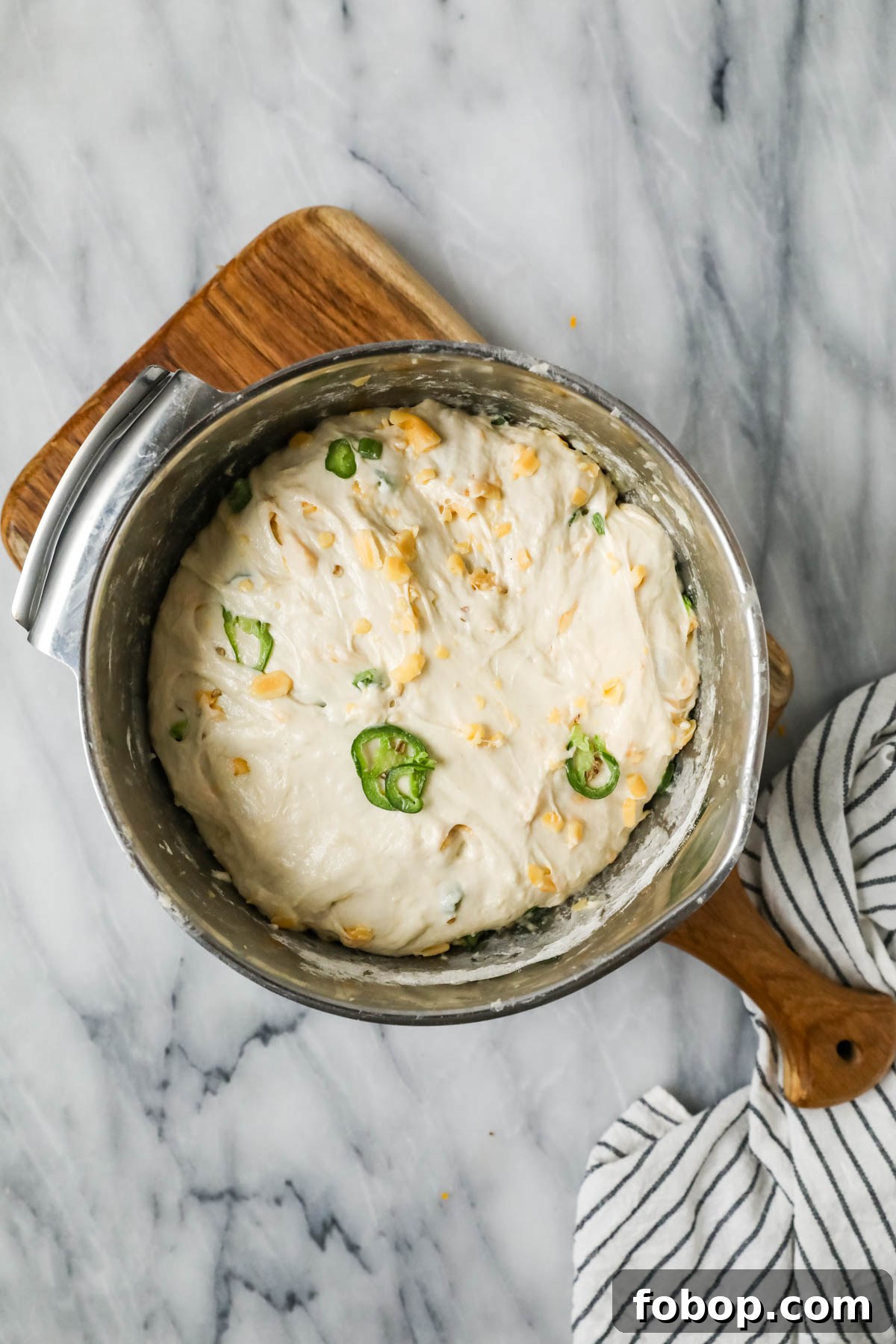 Overhead view of a bowl of dough made with cheddar and jalapenos after rising.