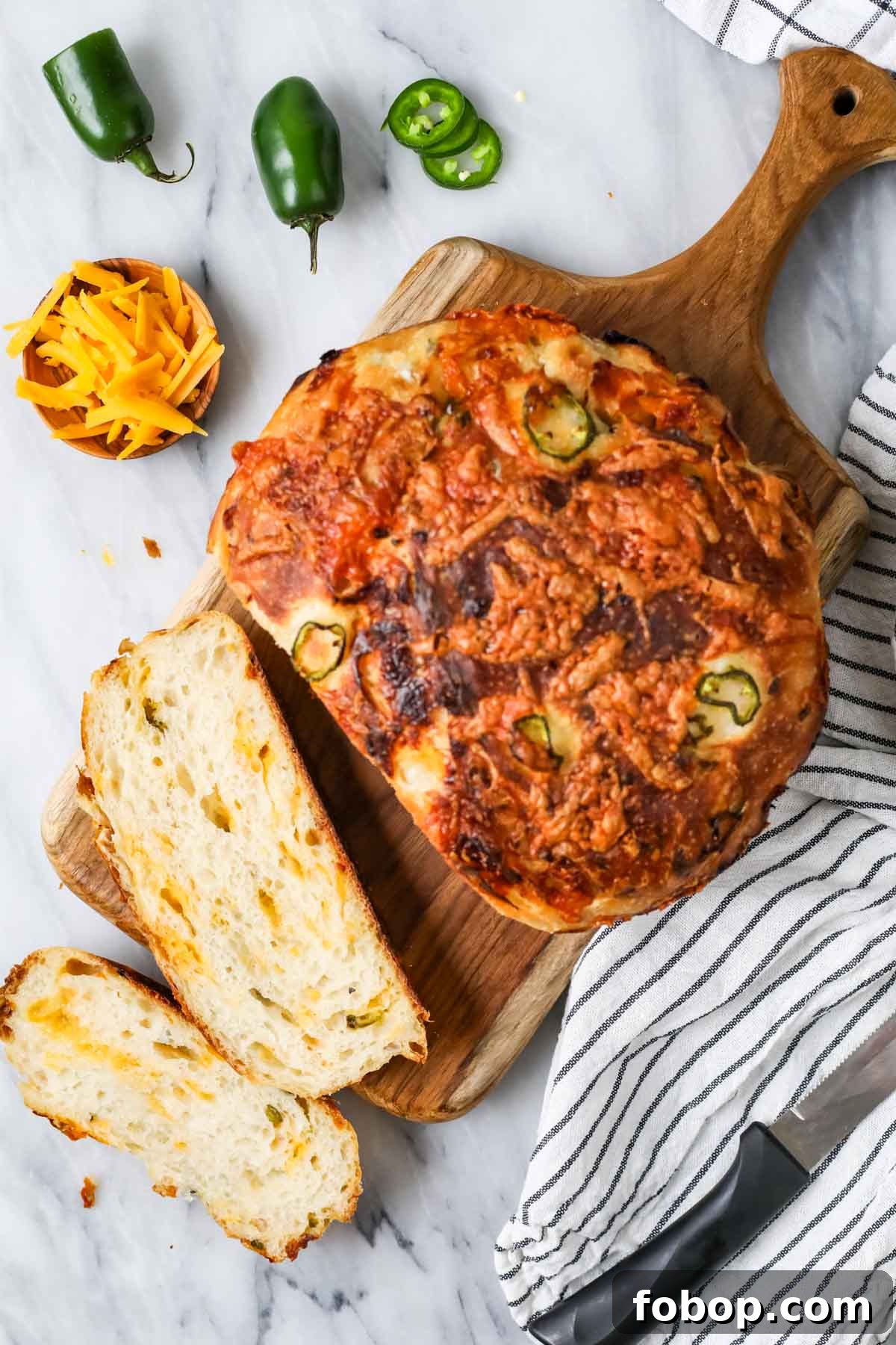 Overhead view of a loaf of sourdough cheddar jalapeno bread that's been cut into a few slices.