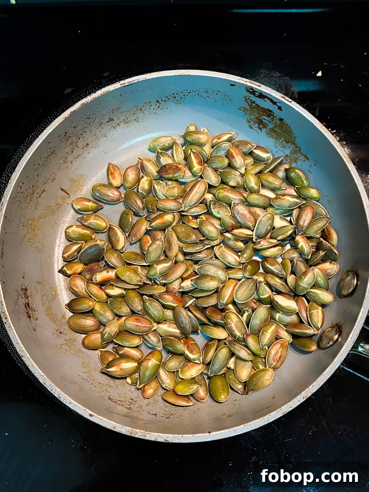 Spinach & Butternut Squash Salad with Smoky Mushroom Bacon and Vegan Feta 8 Photo of toasted pumpkin seeds in a pan.
