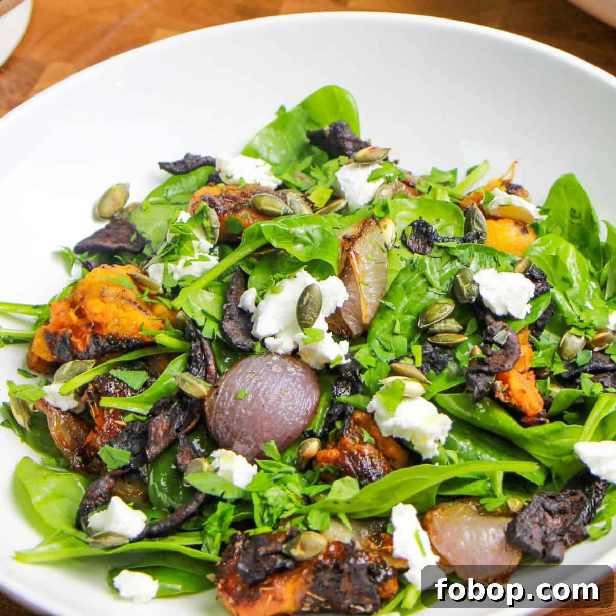 Spinach & Butternut Squash Salad with Smoky Mushroom Bacon and Vegan Feta 10 Photo of vegan spinach and roasted butternut squash salad with mushroom bacon, all mixed in a bowl ready to eat.