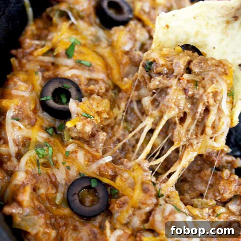 close up of a chip scooping some cheesy taco dip