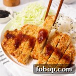 Picking up a piece of air fried chicken katsu with chopsticks.