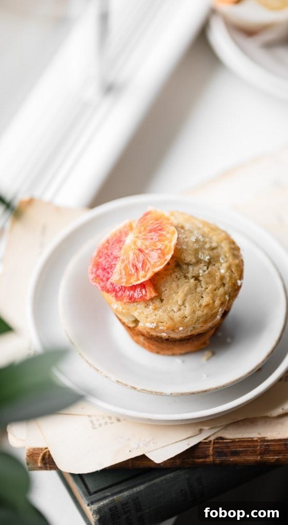 Blood Orange Coconut Muffins with Zesty Glaze 5 Single muffin topped with a sliced orange on white plate.