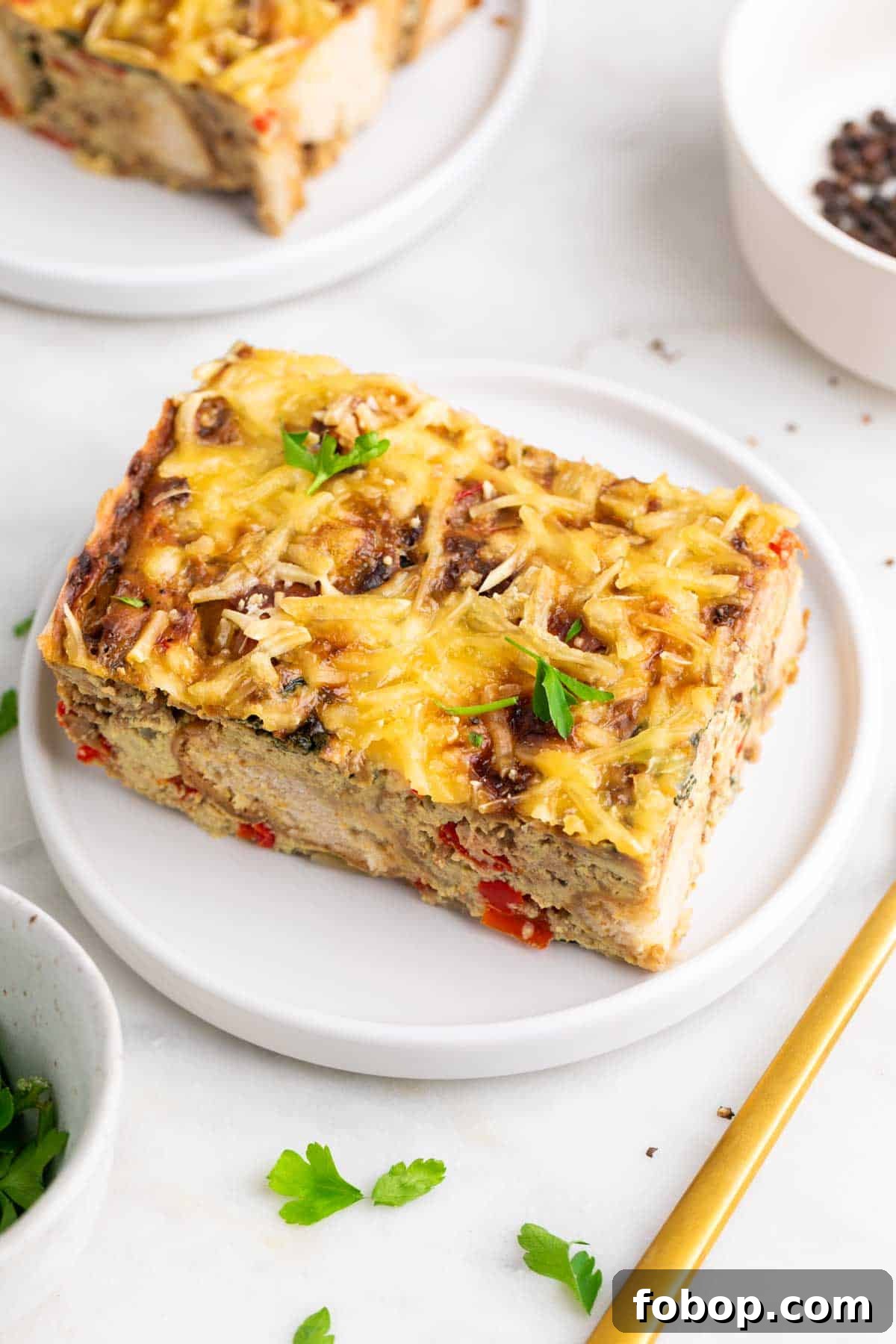 Slice of vegan breakfast casserole on a plate garnished with parsley.