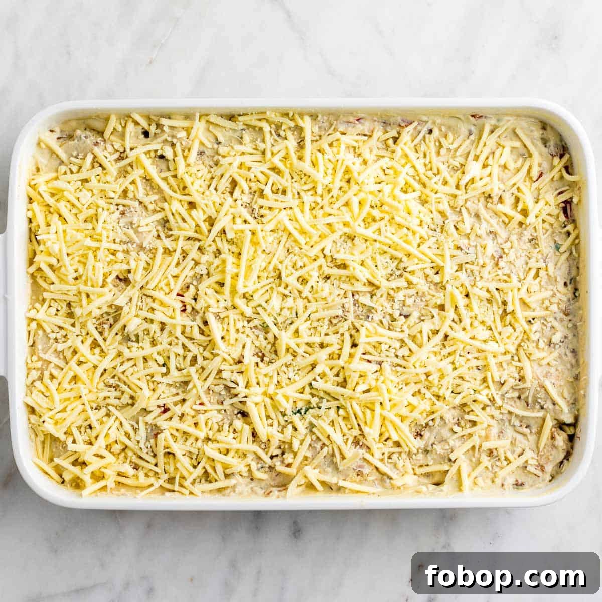 Breakfast casserole topped with vegan cheese before baking.