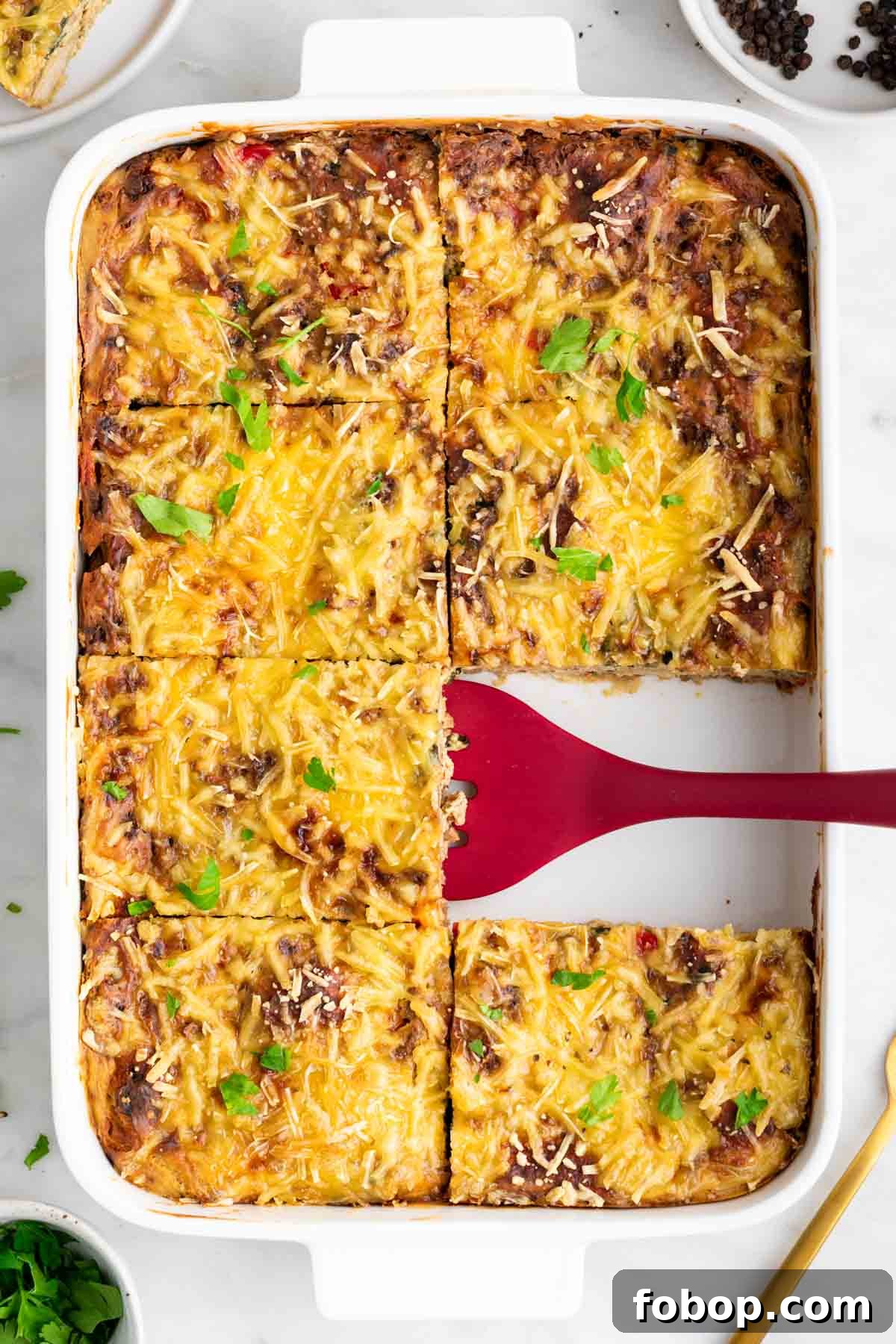 Vegan breakfast casserole cut into squares with a spatula.