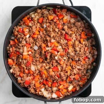 Cooked vegan sausage, onion, and red bell pepper in a skillet.