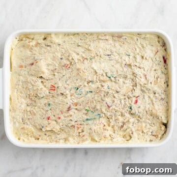 Bread, vegetables, vegan sausage, and tofu mixture combined in a baking dish.
