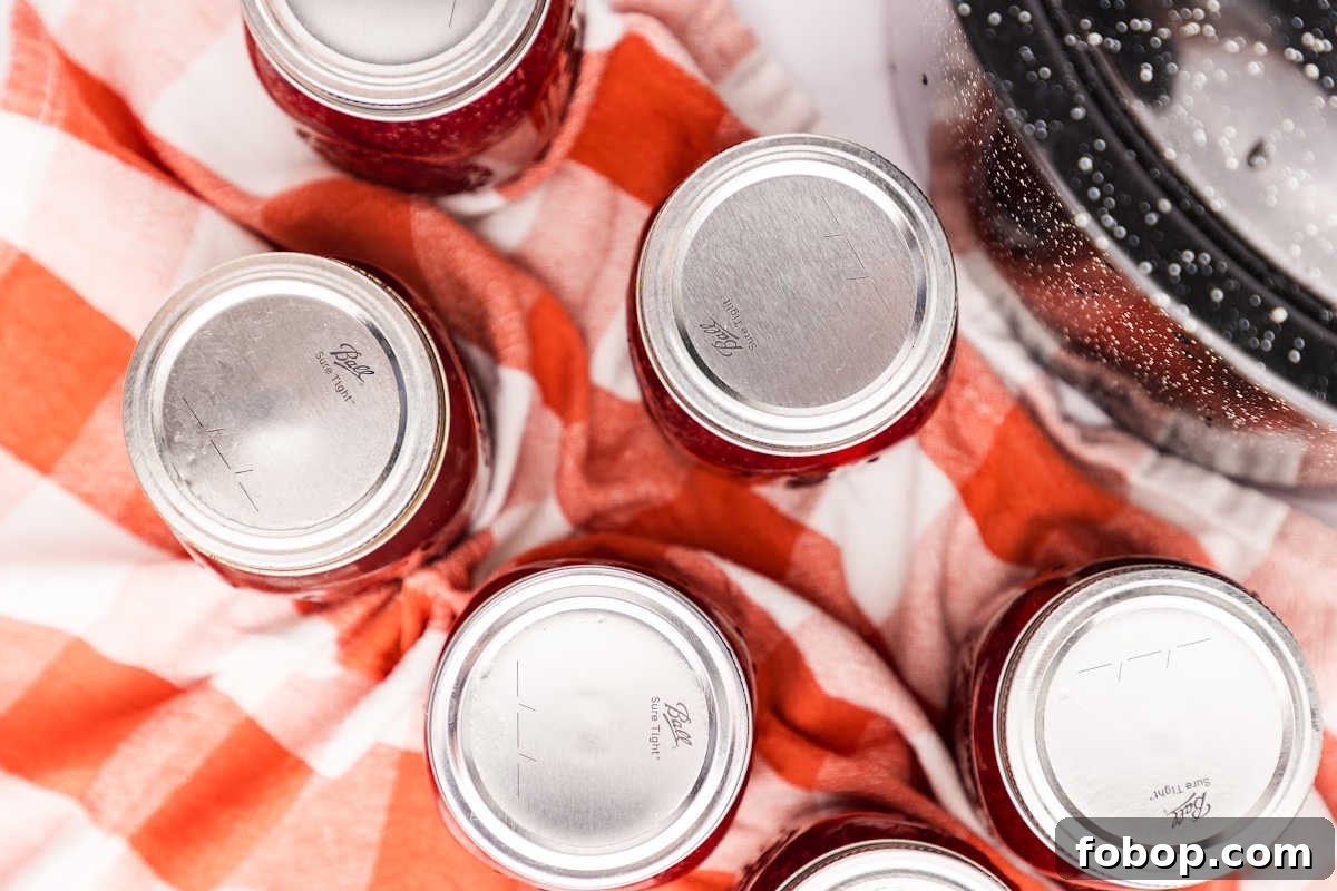 Homemade Cherry Pie Filling for Water Bath Canning: Step-by-Step Guide 11 jars cooling on red and white towel.