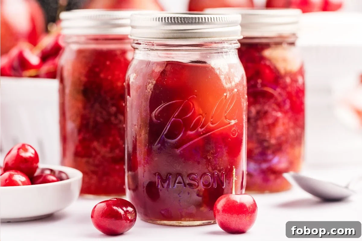 Homemade Cherry Pie Filling for Water Bath Canning: Step-by-Step Guide 12 Close-up of a jar of cherry pie filling with additional jars blurred in the background.