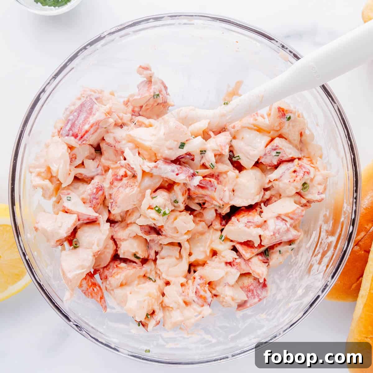 Classic Maine Lobster Roll Recipe: How to Make Authentic Lobster Rolls 6 Lobster salad in a glass bowl with white spatula.