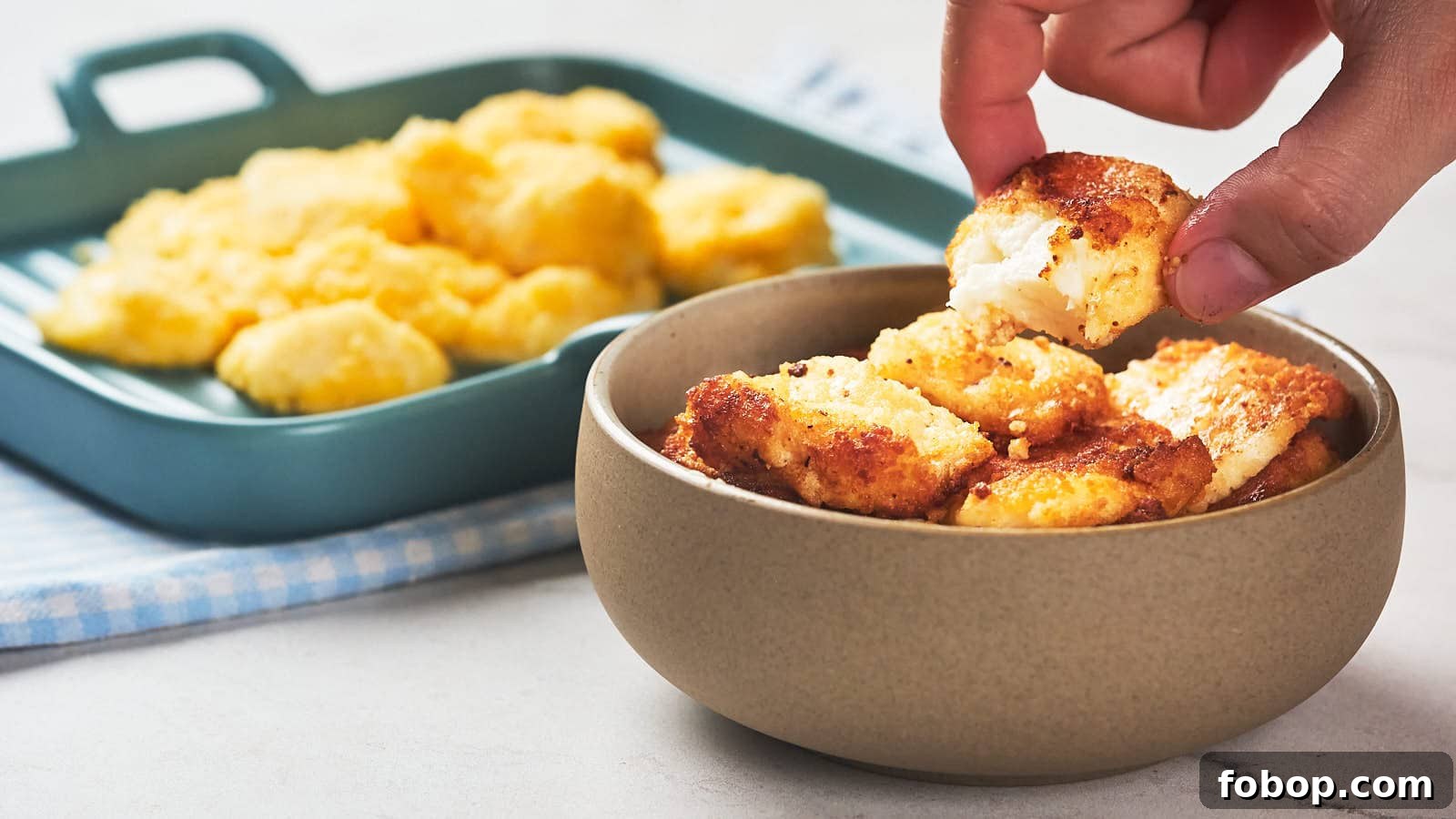 13 Delicious Low-Carb Snacks That Beat Potato Chips 10 A hand picks up a piece of fried cheese curd from a bowl.