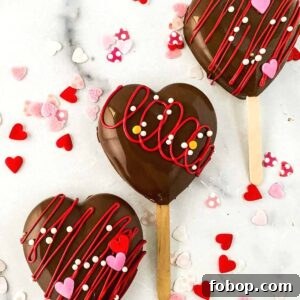 closeup view of three heart shaped cakesicles with sprinkles on a marble background