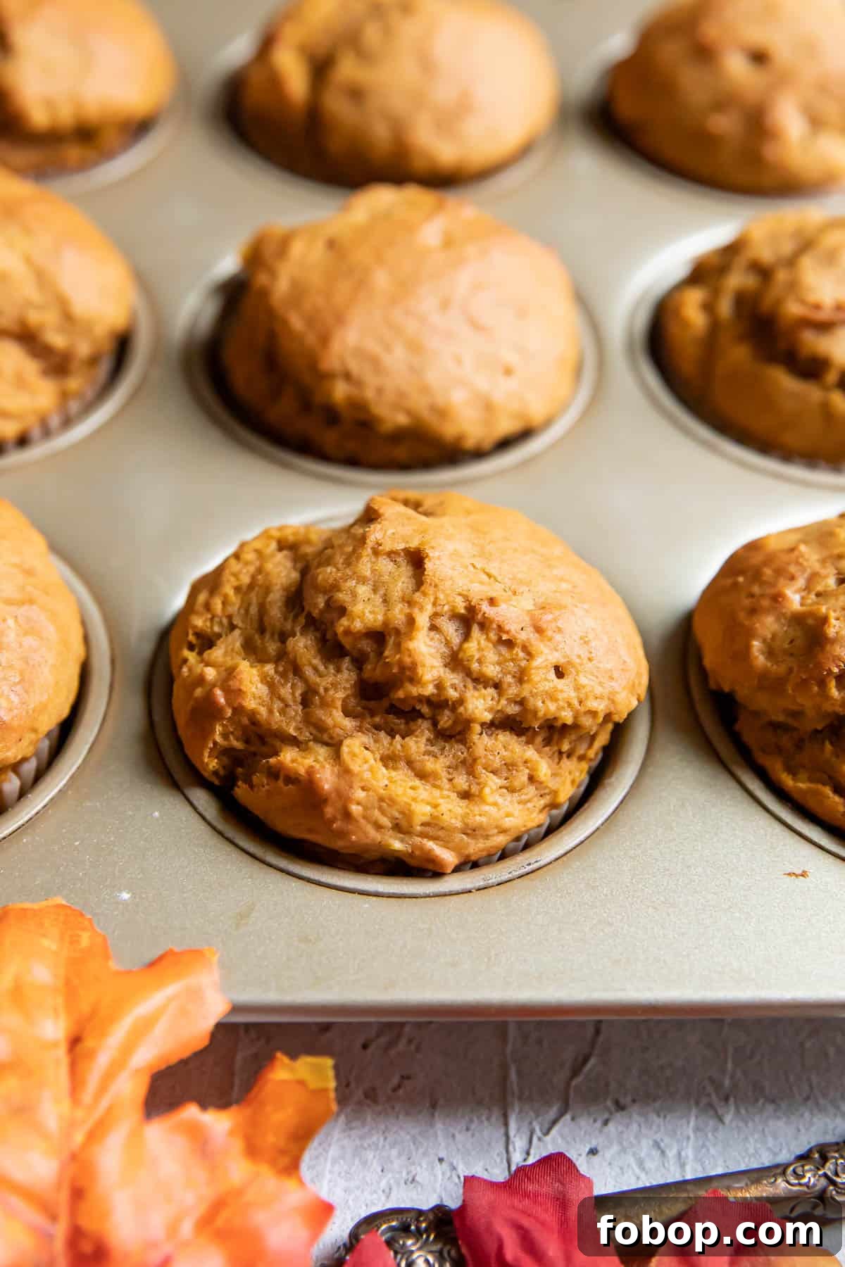 Moist Pumpkin Muffins with Warm Spices — Simple Fall Recipe 4 pumpkin muffins in a muffin tin.