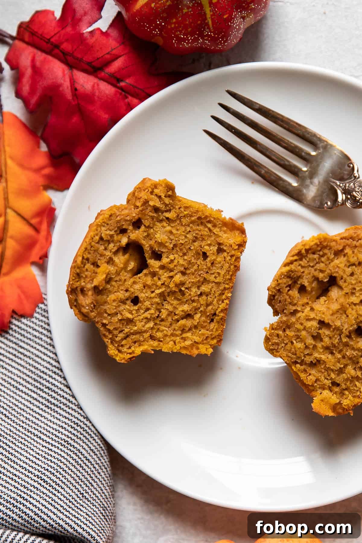 Moist Pumpkin Muffins with Warm Spices — Simple Fall Recipe 8 pumpkin muffin cut in half on a plate.