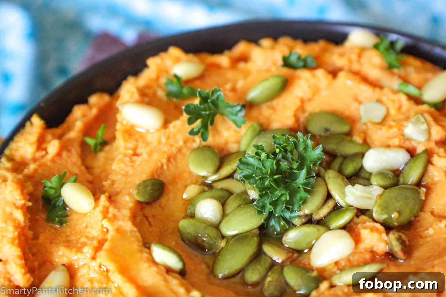 Creamy Pumpkin Hummus Recipe for Fall Entertaining 2 Pumpkin hummus in black bowl garnished with pumpkin seeds and pine nuts