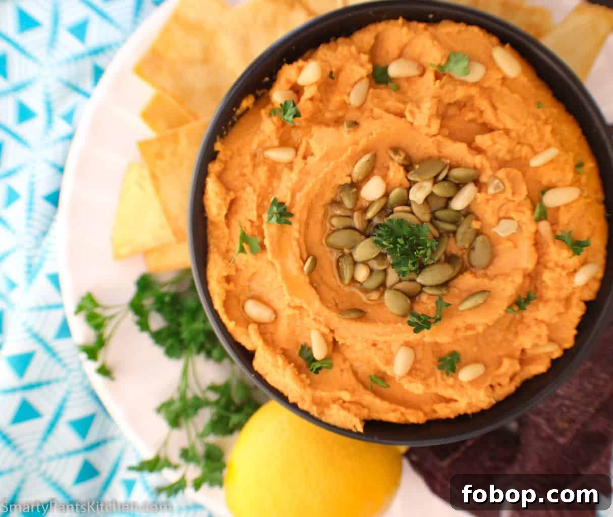 Creamy Pumpkin Hummus Recipe for Fall Entertaining 4 Pumpkin hummus in black bowl garnished with pepitas and pine nuts