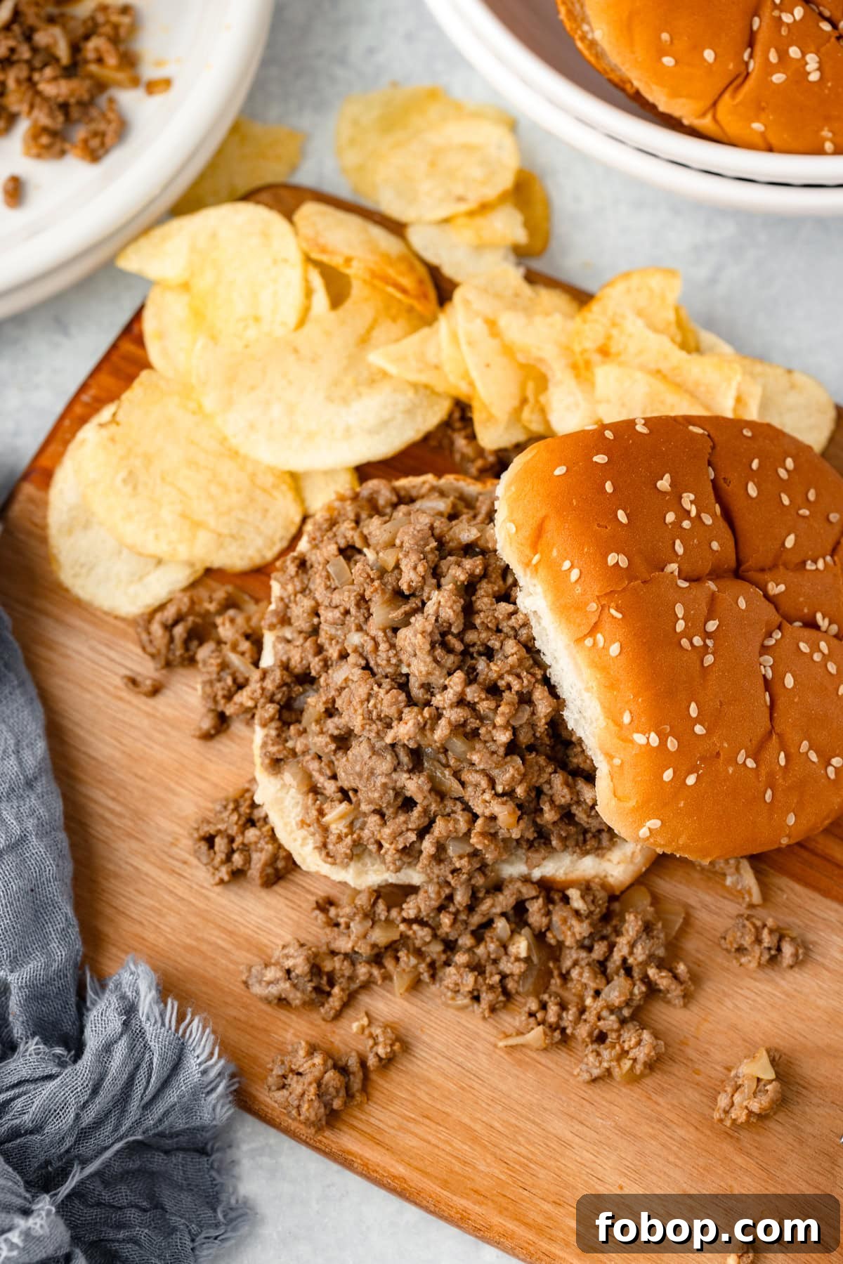 Savoury Loose Meat Sandwich Recipe: Classic Midwestern Sloppy Joe Alternative 7 A loose meat sandwich served open face with the bun on the top to the side. On a wood cutting board, served with chips.