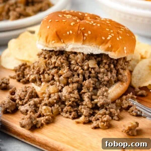 Savoury Loose Meat Sandwich Recipe: Classic Midwestern Sloppy Joe Alternative 8 Seasoned, cooked ground beef on a hamburger bun with it spilling over onto a wood cutting board.