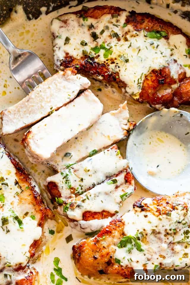 Instant Pot pork chops are juicy, tender, hearty, and rich, with a golden brown sear and a tangy and herby ranch cream sauce. A pork chop cut into slices, with a fork running through two slices, next to three whole pork chops, all covered in a cream sauce and herbs.