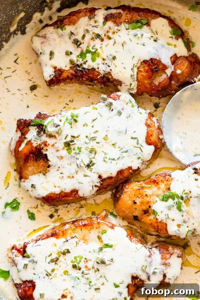 Instant Pot pork chops are juicy, tender, hearty, and rich, with a golden brown sear and a tangy and herby ranch cream sauce. Overhead view of four pork chops smothered in cream sauce, in a pot with more sauce.