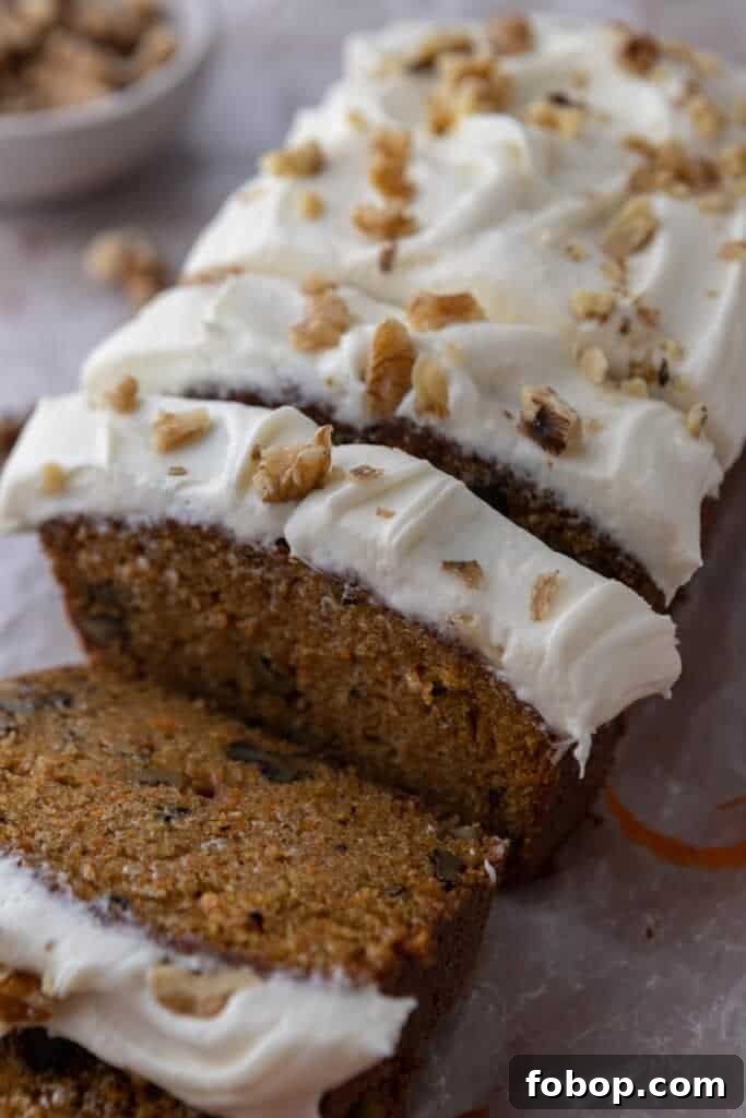 Moist Carrot Loaf Cake Recipe with Oil (Loaf Pan Method) 2 Moist carrot cake loaf with cream cheese frosting and walnuts sliced on parchment paper