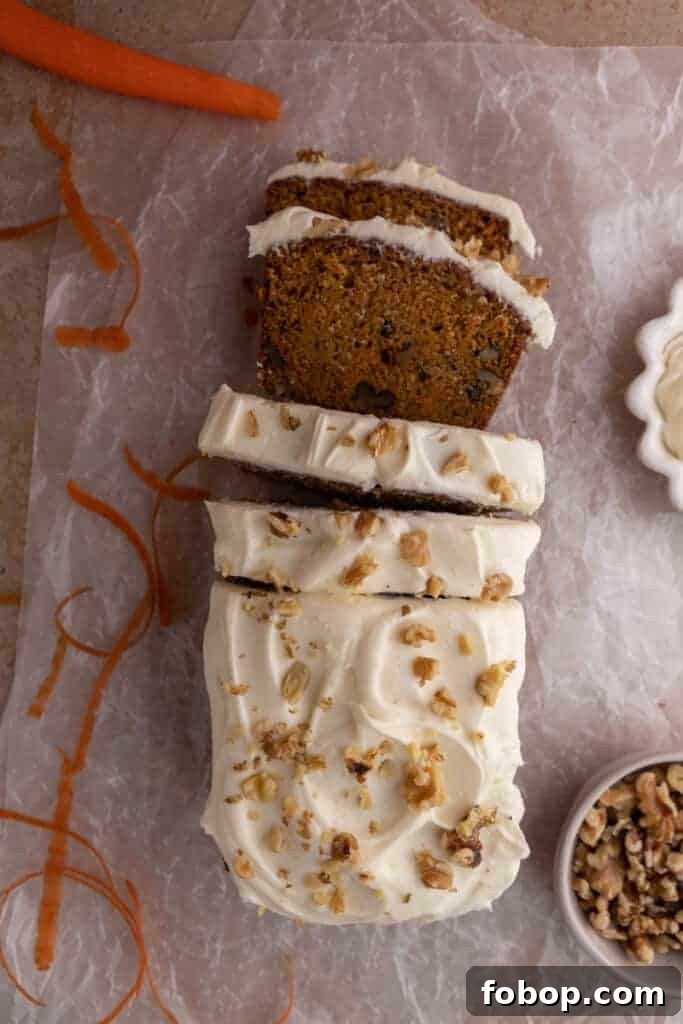 Moist Carrot Loaf Cake Recipe with Oil (Loaf Pan Method) 12 Sliced carrot cake loaf with cream cheese frosting on parchment paper