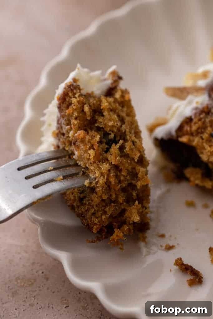 Moist Carrot Loaf Cake Recipe with Oil (Loaf Pan Method) 13 Fork lifting a bite of moist carrot cake loaf with cream cheese frosting