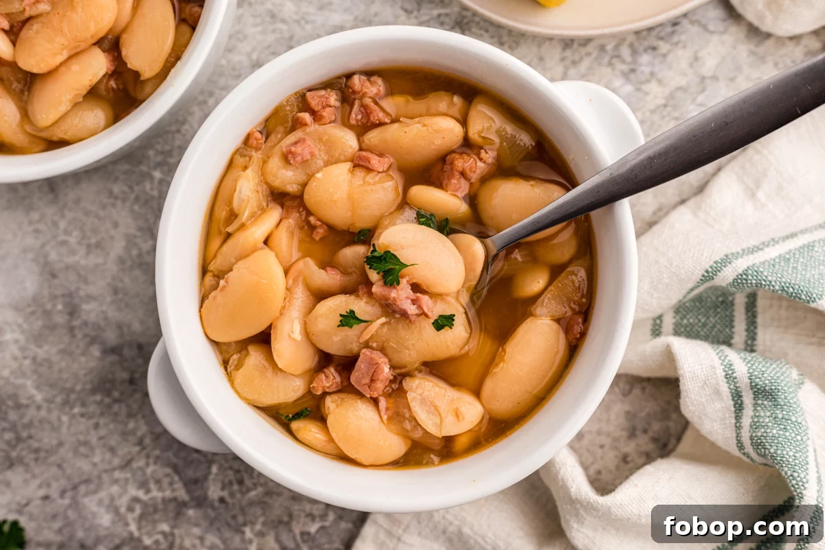 Creamy Slow Cooker Lima Beans Recipe for Weeknight Dinners 7 overhead shot of slow cooker lima beans in a bowl with a spoon.