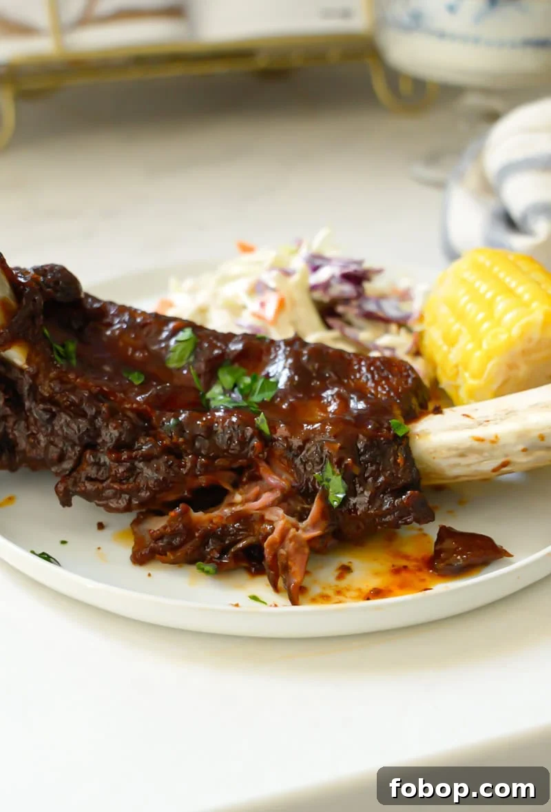 Oven-Baked Beef Ribs Recipe: Tender, Flavorful Results 3 easy beef ribs with bbq sauce on a plate with coleslaw and corn