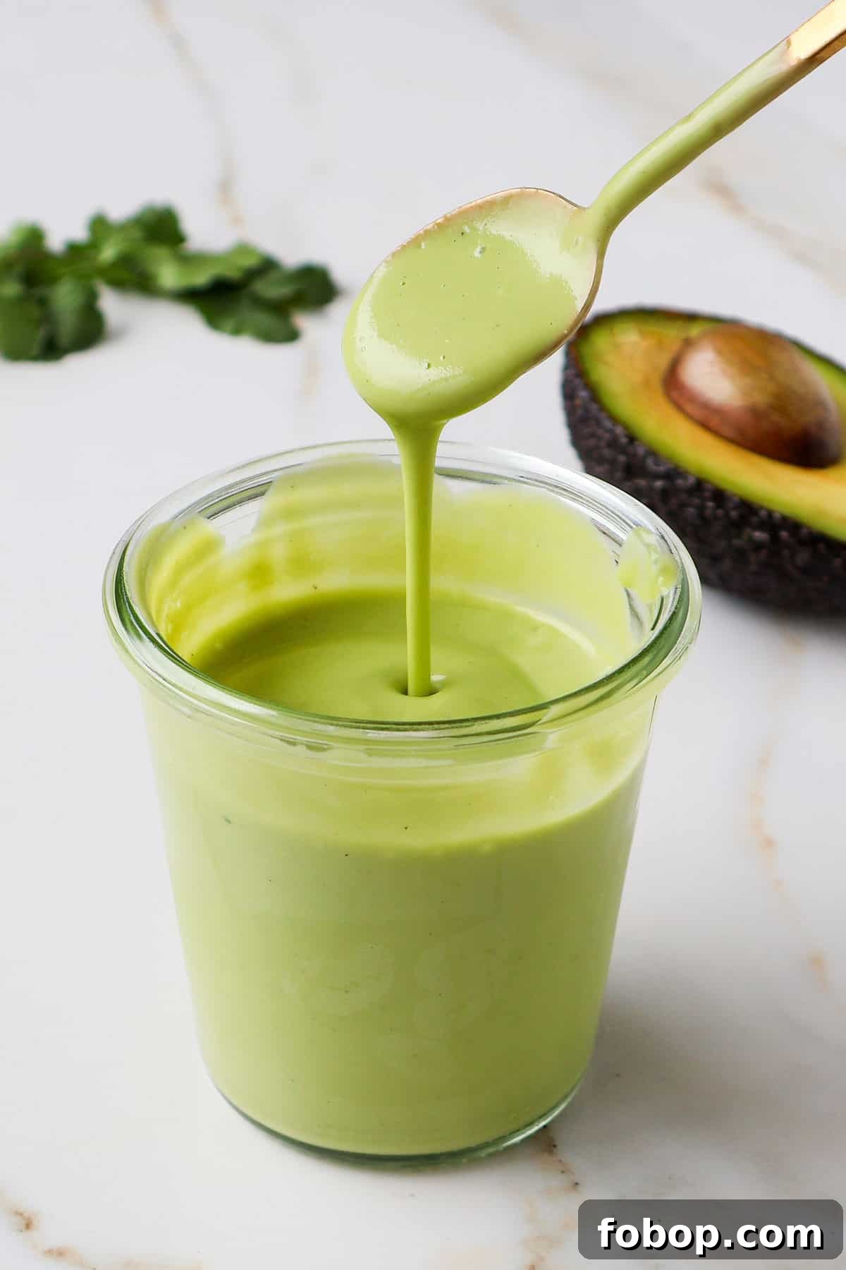Avocado dressing poured with a spoon.
