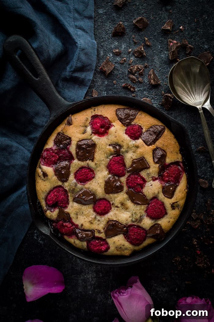 Vegan Chocolate Raspberry Skillet Cookie for Two – Decadent Dessert 6 Chocolate raspberry skillet cookie for two on a black background with two spoons and a grey cloth.