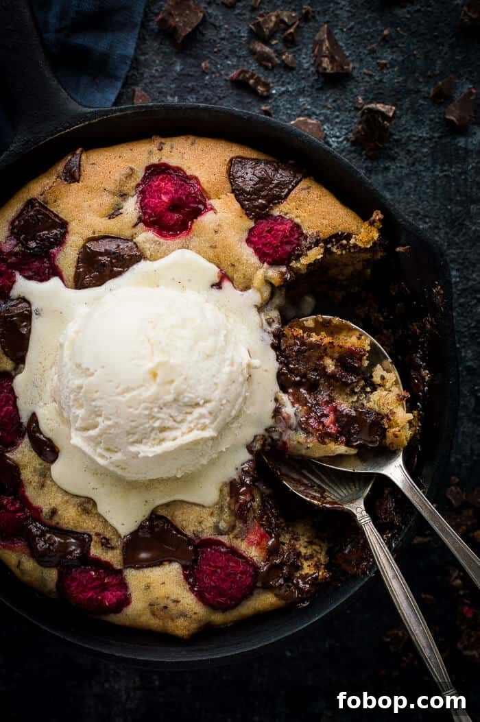 Vegan Chocolate Raspberry Skillet Cookie for Two – Decadent Dessert 7 Close up of partially eaten vegan chocolate skillet cookie for two with vanilla ice cream on top and two spoons.