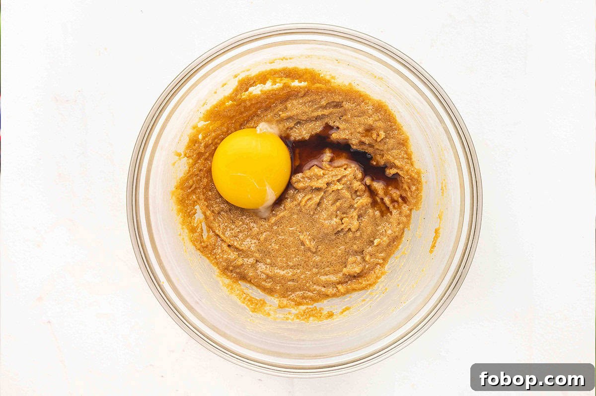 Egg and vanilla added to peanut butter in a bowl