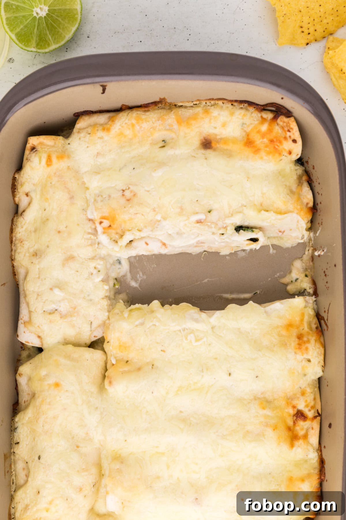 Baked Creamy Chicken Spinach and Mushroom Enchiladas pan of creamy chicken spinach and mushroom enchiladas with one taken out